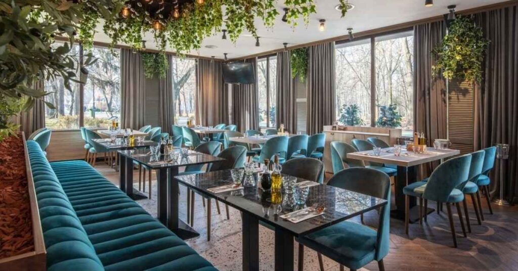 Elegant indoor restaurant with teal seating and hanging greenery.