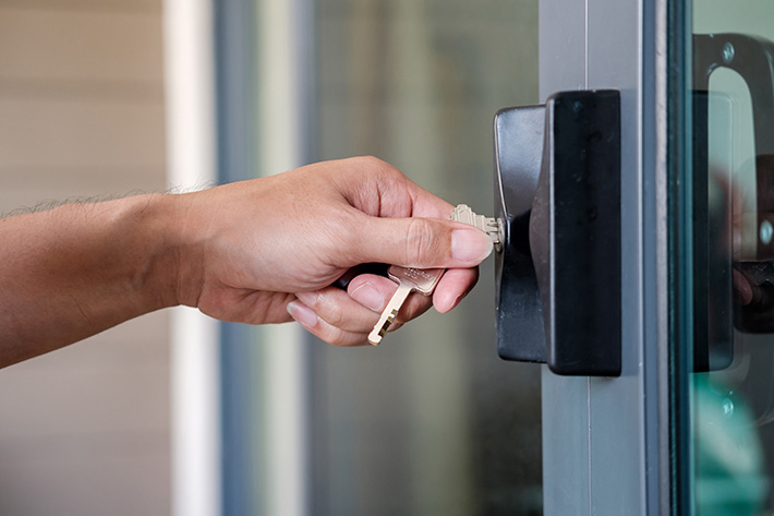 Hand inserting a key into a door lock.